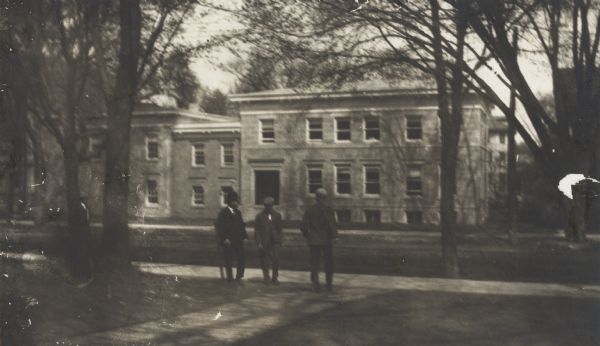 Exterior of Administration building at Park and State Streets. Three men wearing hats are standing near the sidewalk.