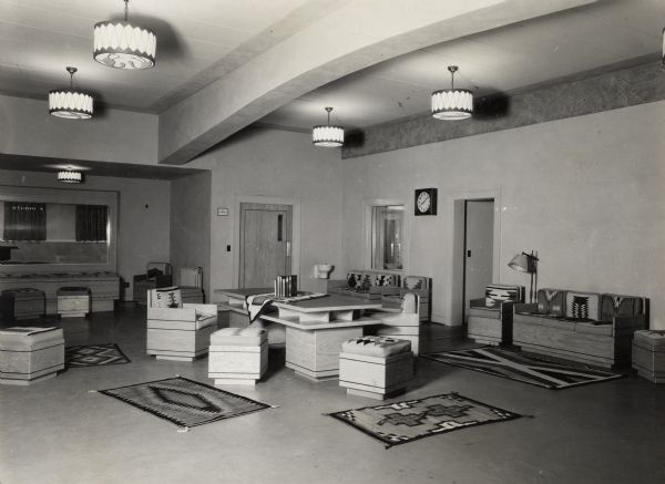 Visitor's lounge of Radio Hall, the campus home of state stations WHA and WHA-FM, on the University of Wisconsin-Madison campus. The room is decorated in a Southwest motif, and the petroglyphs in the frieze along the top of the right wall are reproductions of originals made on cave walls by prehistoric Indians in Wisconsin. The weavings are genuine Navaho creations from the Southwest. A window on the left is marked with a sign, "Studio A," and in the right wall is another window labeled with the sign, "Studio C."