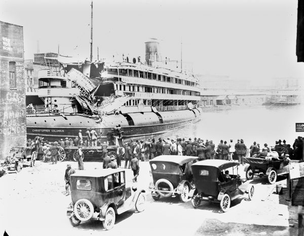 Large crowd looking at the damaged <i>Christopher Columbus</i> cruise vessel at dock. Constructed in 1893, the <i>Christopher Columbus</i> was the only passenger-carrying whaleback steamer ever built. Eighteen passengers died when the ship hit a water tower on the bank of the Milwaukee River on June 30th, 1917.

