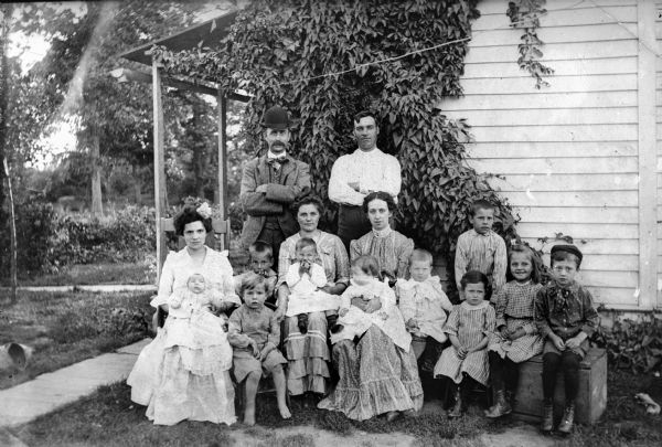 Large family group posed in yard near house.