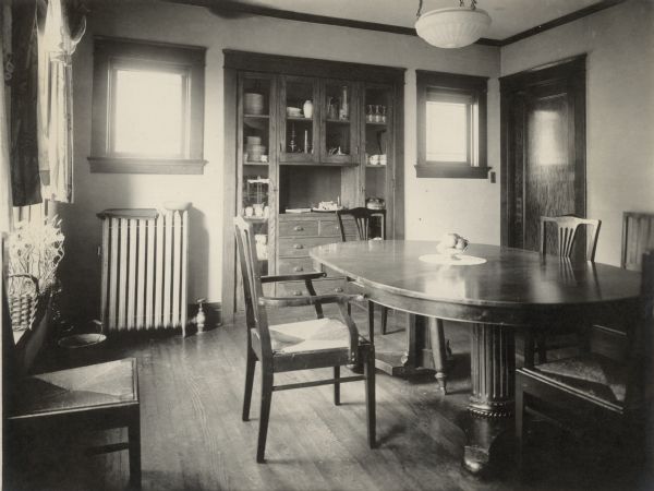 The dining room of the Richard Lloyd Jones residence, 1010 Walker Court (now clled Rutledge Court), showing dining table, light fixture, and built-in china cabinet.