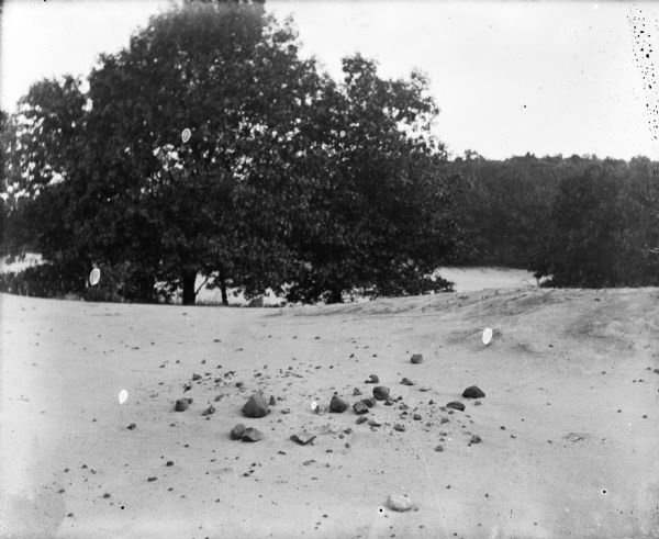 A barren area of sandy soil and rocks identified as the site of an Indian village near Okee.