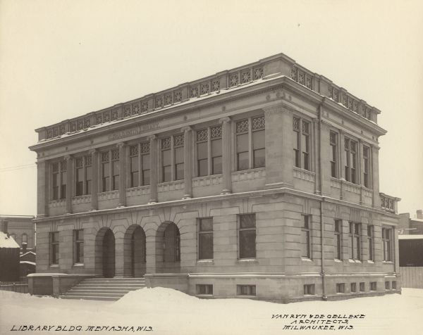 Elisha D. Smith Library Exterior view from road of the Elisha D. Smith Library in winter. The library opened in 1898 funded with a gift of $20,000 from E.D. Smith. Over the main entrance, at the roof line, it reads: "Elisha D. Smith Library." Lower left of photograph reads: "Library Bldg. Menasha, Wis." and lower right reads: "Van Ryn & de Gelleke Architects, Milwaukee, Wis." The building is of stone with three large stone arches at the entrance.