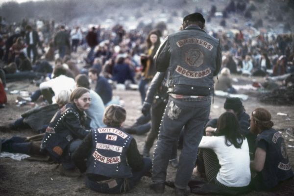 Group of Seated Bikers A group of bikers in leather jackets that read "Drifters MC Property of Sugar Bear" and "Drifters MC Rockford" seated in the Sound Storm audience.