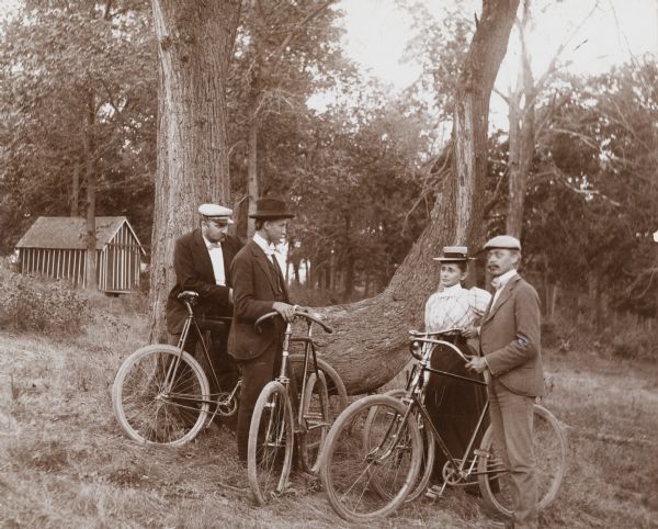 Mr. and Mrs. H. Schildhauer and Louis and Henry Harder stand near a large tree and rest from a bike ride on Mendota Drive.