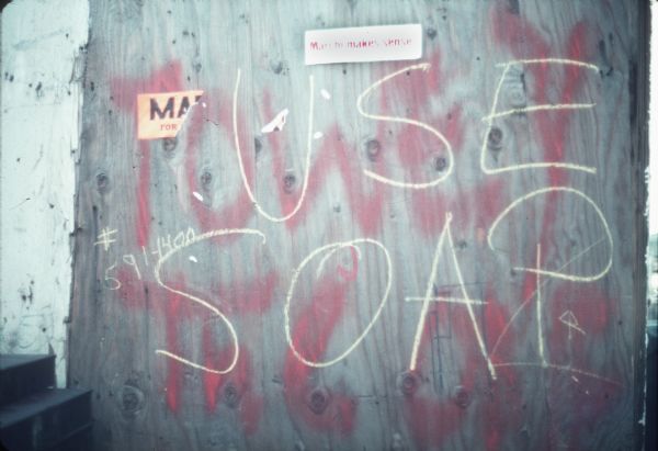 Two different messages on a wall. One says: "Use Soap" and the other "Towey T..." In addition a small sign reads: "Marchi Makes Sense!"