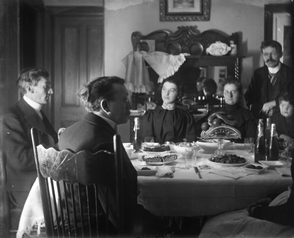 A group of family members sitting at a table laden with food for a New Year's dinner.