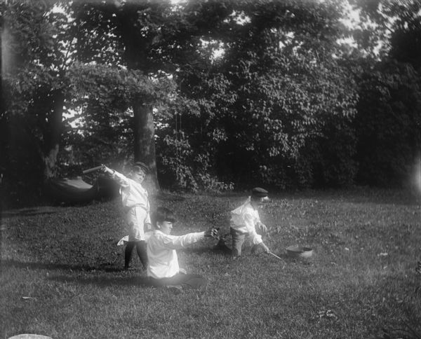 Syl, Gordon and Harold playing with fireworks on a lawn. A hammock strung between two trees is visible in the background.