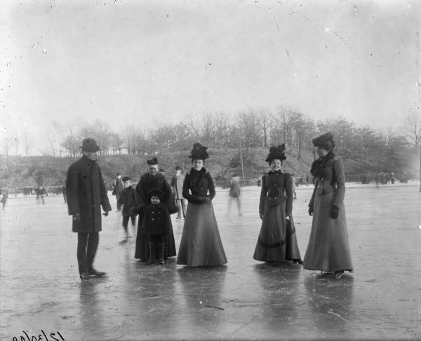 Winter scene with four women, a man and a child, all well-dressed, posing on the ice wearing ice skates. Other skaters are behind them. Caption reads: "Syl, Grandma, and others posing on skates."<p>The boy is Harry Sylvester Dankoler (1895-1908) standing in front of his grandmother Matilde (Wahe/Wehl) Dankoler/Damkoehler (1832-1918).</p>