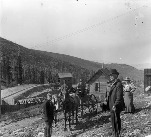 People gathered around a horse-drawn buggy on the dividing line between the Ferris-Hagerty property and the Leighton-Wyoming mines. Harry Dankoler is to the right in the foreground holding the shutter release mechanism. In the background are hills with felled trees.