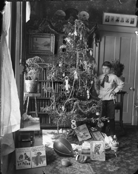 Syl, son of the photographer, stands next to a Christmas tree surrounded with presents, including a punching-bag, books and boxing gloves.