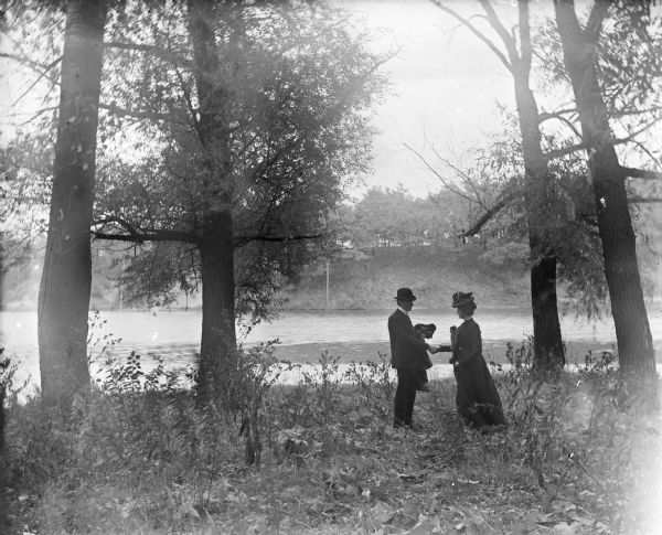 Aunt Helen and Will shaking hands in a clearing near the edge of a small lake at the Garden Place.