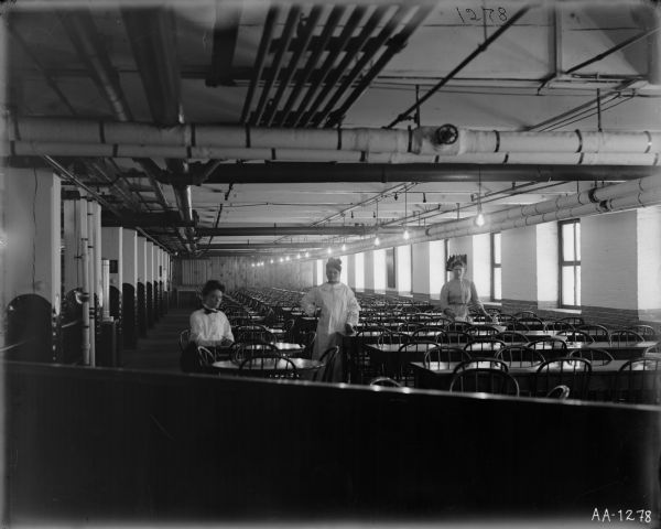 Three women standing in a factory cafeteria, probably at the McCormick Reaper Works.