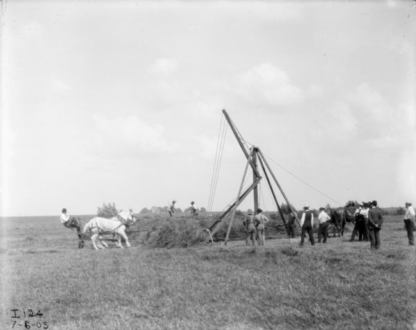 Men Using Horse-Powered Hay Stacker View across field towards men using a horse-powered hay stacker. Adapted, mounted on jin-pole. The horse is straining to lift the load.