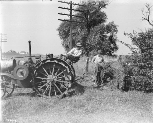 Men Pulling Tree Stump with Titan Tractor Two men are working to remove a tree stump using a Titan tractor.