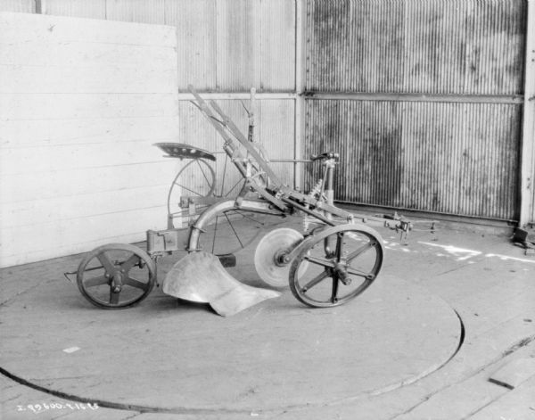 Sulky Plow Sulky plow displayed on the floor of a building.