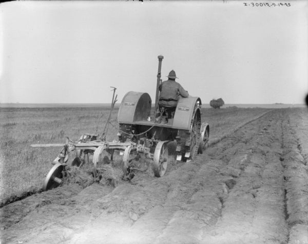 Man on Tractor Disking Field Rear view of a man driving a tractor disking a field.