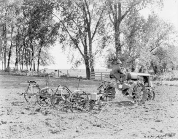 Man Driving Tractor-Drawn Planter View across field towards a man driving an IHC tractor to pull a planter.