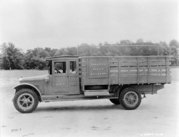 Canadian Pacific Express Truck Left side view of a truck parked on a road. A spare tire can be seen on the side of the truck on a shelf with an open door.