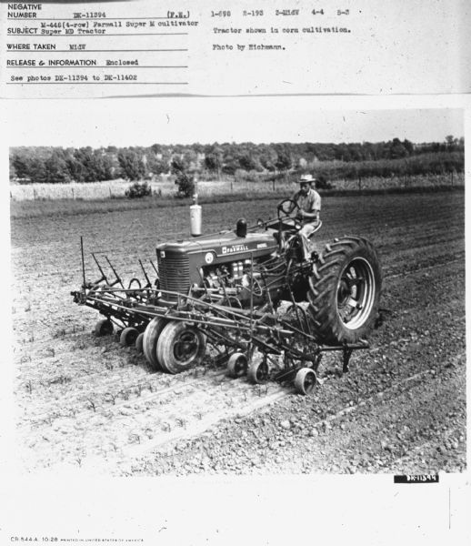 Super MD Tractor Three-quarter view from front right of a man driving a Super MD Tractor.
Subject: "Super MD Tractor M-448 (4-row_ Farmall Super M cultivator." Where Taken: "MidW." Information with photograph reads: "Tractor shown in corn cultivation. Photo by Eichmann."