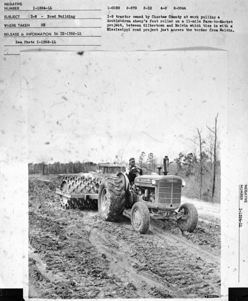 I-9 — Road Building View towards a man driving an I-9 tractor. Subject: "I-9 — Road Building." Where Taken: "SE." Information with photograph reads: "I-9 tractor owned by Choctaw County at work pulling a double-drum sheep's foot roller on a 11-mile Farm-to-Market project, between Gilbertown and Melvin which ties in with a Mississippi road project just across the border from Melvin."