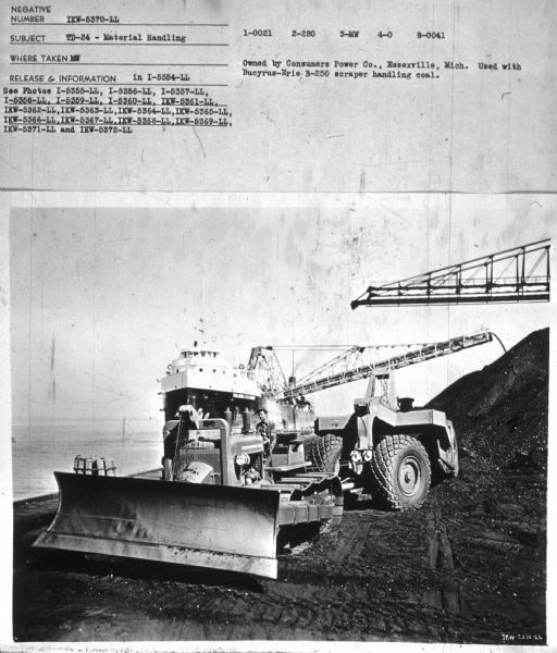 TD-24 — Material Handling View towards a man driving a TD-24. In the background are cranes, and a ship at the shoreline. Subject: "TD-24 — Material Handling." Where Taken: "MW." Information with photograph reads: "Owned by Consumers Power Co., Essexville, Mich. Used with Bucyrus-Erie B-250 scraper handling coal."