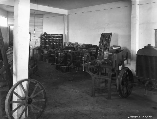 Interior view of repair shop at implement store. A tractor is on the far right. The wheel of a vehicle is in the left foreground.