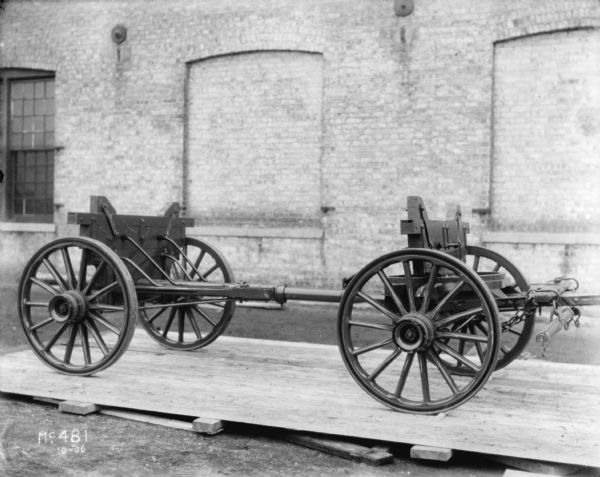 Wagon on Wood Pallet at McCormick Works View of a wagon, without wagon box, set up on a wooden pallet outdoors. A brick factory building is in the background.