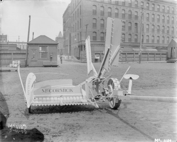 Milwaukee Reaper at McCormick Works Milwaukee Reaper outdoors in the yard at McCormick Works. There is a small building and a tall, wooden fence in the background. Beyond are brick buildings.