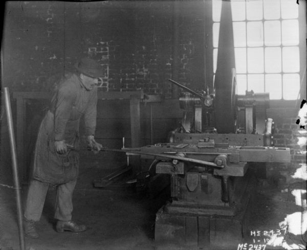 Man Forming Metal Man forming metal inside a factory building.