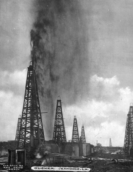 A view of oil wells in Louisiana. On October 7, 1901, oil gushed to a height of seventy-five or eighty feet, continuing for seven hours. Caption reads: "Gusher, Jennings, LA."