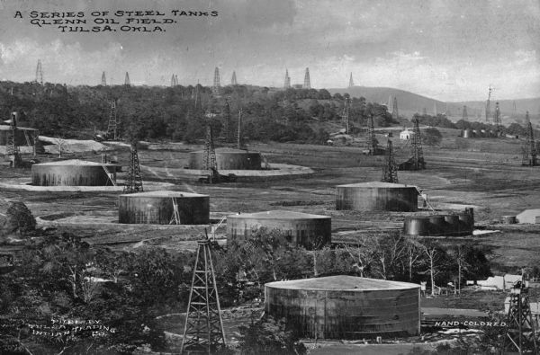 A view of rows of oil derricks and steel tanks at Glenn Pool Oil Field where oil was first discovered on November 22, 1905 by Robert Galbreath and Frank Chesley. The Glenn Pool has produced 340 million barrels of oil since that day. Caption reads: "A Series of Steel Tanks Glenn Oil Field, Tulsa, Okla."