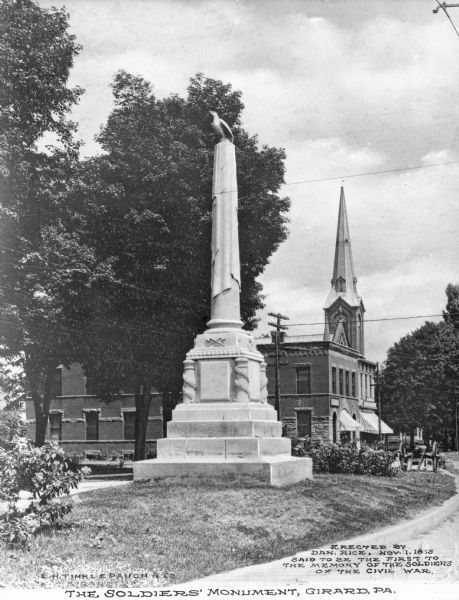 A view of a The Soldiers' Monument, erected on November 1, 1865 by Dan Rice, a famous circus man. The memorial is said to be the first built honoring the soldiers of the Civil War. Caption reads: The Soldiers' Monument, Girard, PA." Text on right reads: "Erected by Dan. Rice, Nov. 1, 1865. Said to be the first to the memory of the soldiers of the Civil War."