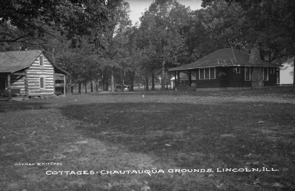 View of the Chautauqua Grounds, founded in 1874. A log cottage stands on the left, and another wooden cottage can be seen on the right. Caption reads: "Cottages, Chautauqua Grounds, Lincoln, Ill."