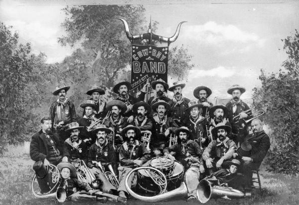 The Original Dodge City Cowboy Band Group portrait of the members of the original Dodge City Cowboy Band, organized 1881-1882. Band members hold musical instruments, and a banner stands behind the back row, decorated with animal horns.