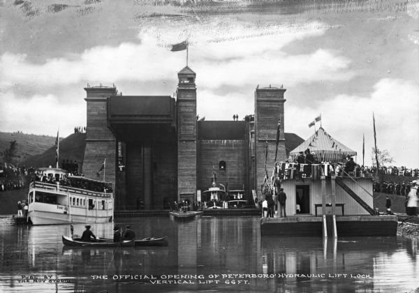 Official opening of the sixty-six foot Peterboro hydraulic lift lock, built in 1904 on the Trent Canal. People gather in boats and along the shore to celebrate the opening of the canal. Caption reads: "The Official Opening of Peterboro Hydraulic Lift Lock, Vertical Lift 66 FT."