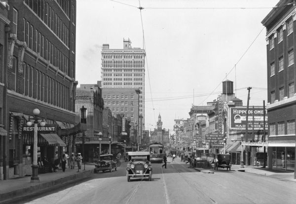 Busy Commercial Center View down a busy commercial downtown street featuring automobiles, cable cars, pedestrians, a restaurant, and the Hippodrome Theater which opened in 1914.