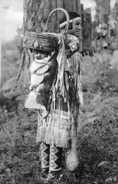 An Apache Native American woman with a baby in a papoose on her back.