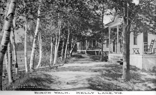 View of two lakeside cottage, which have docks and porches that overlook the lake. Caption reads: "Birch Walk, Kelly Lake, Wis."
