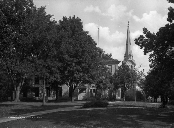 View across lawn toward the chapel at Ripon College. The bottom half of the structure is made of brick and has tall, stained-glass windows. Above this is a wooden tower area with louvered vents with a clock in the steeple above it.