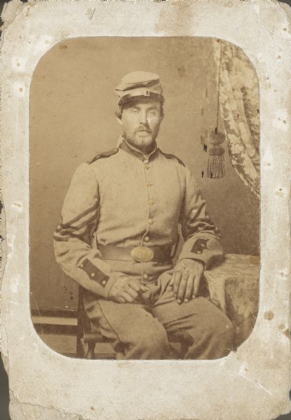 Seated portrait of Corporal Charles Stewart (b. 1832), Company B, 8th Wisconsin Infantry, wearing the one of the grey uniforms in which Wisconsin's first eight regiments left the state. In 1861, the Northern states purchased their own uniforms, and Wisconsin selected grey, possibly because it was the color uniforms of the New York militia where Wisconsin purchased the majority of its uniforms. Not until the fall of 1861 did blue become the standard color for Union troops. Stewart, a Greenbush farmer, rose in the ranks and was mustered out in 1865 as Captain.