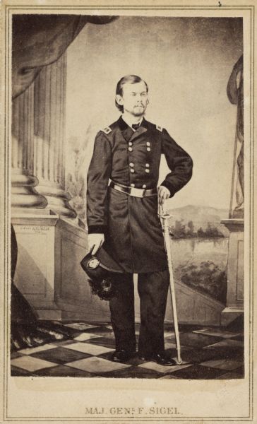 Full-length carte-de-visite portrait of Major General Franz Sigel, posed in front of a painted backdrop.
