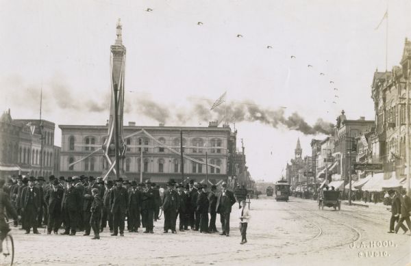 Outdoor view of Union veterans standing near a war memorial in a square downtown.