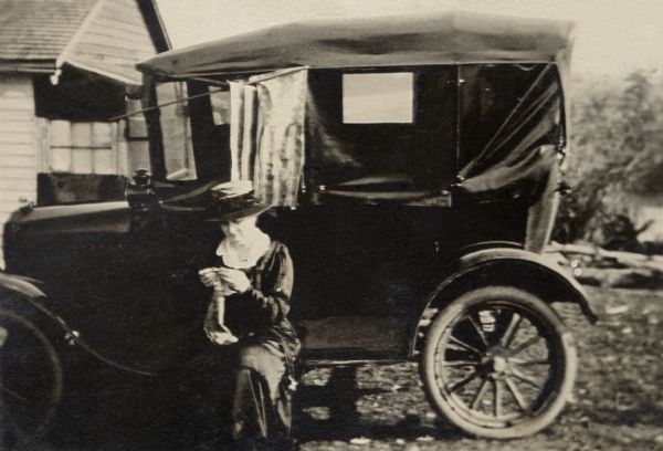 Katherine (Kate) Quinney, Richard Quinney's great aunt, crocheting while seated on the running board of a Ford Model T in the yard of her family's farm.