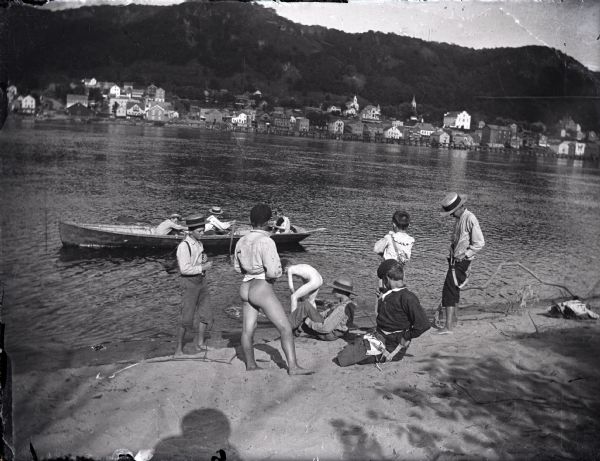 Boys undressing to go swimming in the Mississippi River. Alma, Wisconsin is across the river in the background.