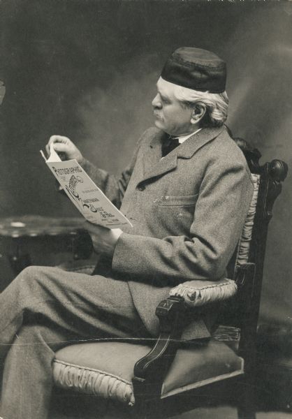 Studio portrait of Gerhard Gesell sitting in a chair reading an issue of the "Photographic Recorder".