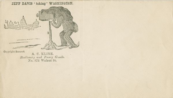 In a play on words, Jeff Davis is "taking" Washington with a camera. He is crouching under the cloth peering through a camera on a tripod. The camera is pointed towards the Capitol buildings. The caption above reads "JEFF DAVIS 'taking' WASHINGTON." Black ink on cream envelope, image on left side.