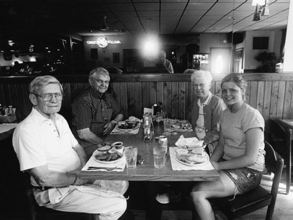 "Brittany was the cook and waitress at Rusty's Pub-N-Grub." From left to right: Ralph "Buddy" Ruecker, Carl Bernhard, Shirley Widmer, and Brittany. Jim Widmer's reflection can be seen in the mirror. 
