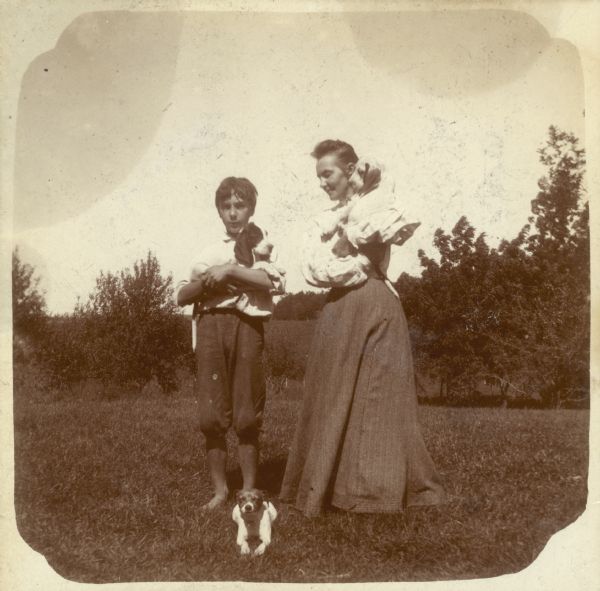 A barefoot Forest Middleton and his mother, Clara, each hold a dog, while a third dog lies at their feet.