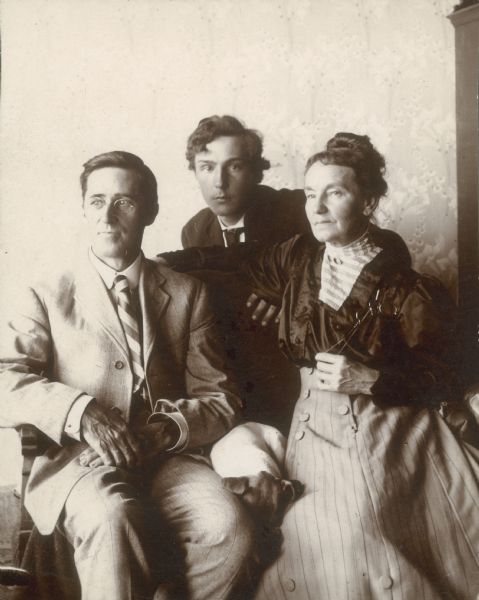 William and Clara Case Middleton sit on a settee; their son Forest leans in between them from behind. A small dog is nestled between William and Clara.